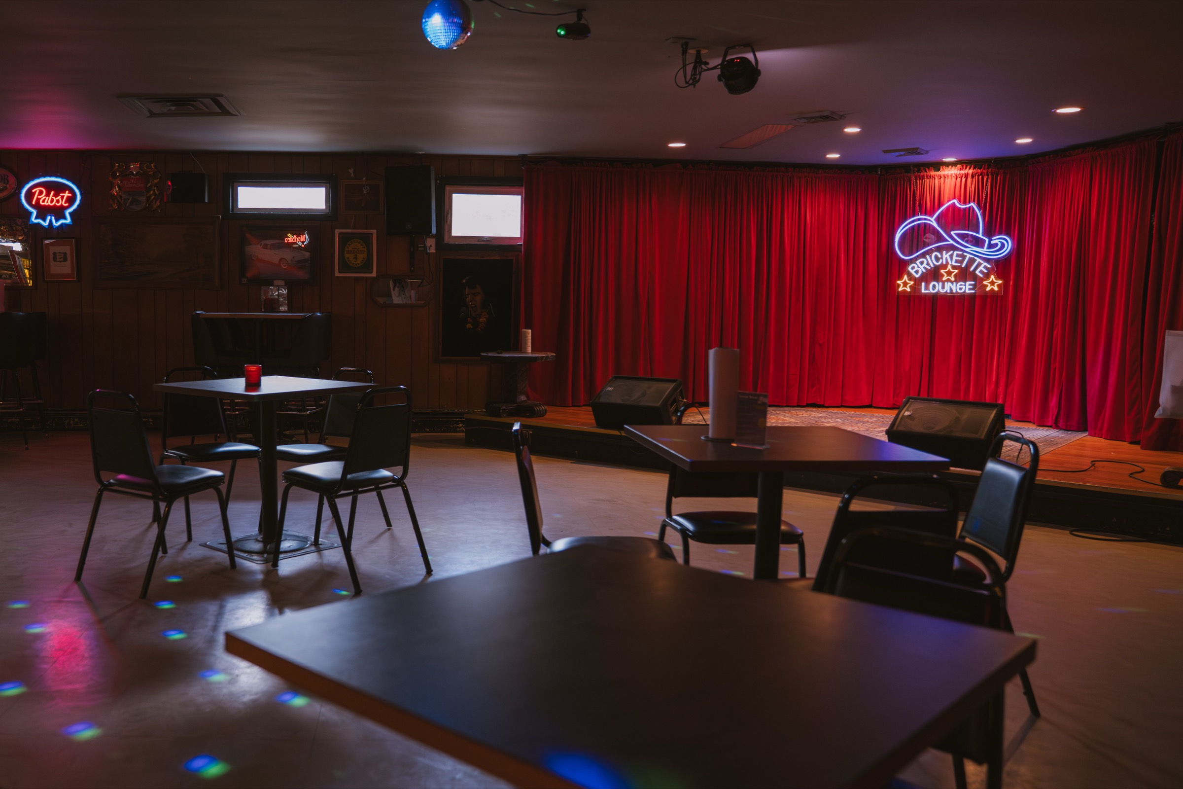 The Brickette Lounge dining floor, tables and stage beneath the neon